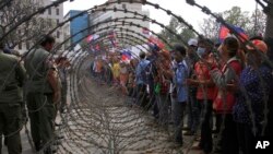 In this file photo, taken on Dec. 30, 2013, Cambodian garment workers, right, are blocked by barbed wire set up by police near the Council of Ministers building during a rally in Phnom Penh, Cambodia. (AP Photo/Heng Sinith)
