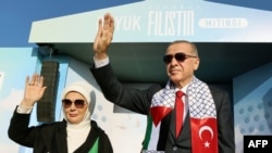 Presiden Turki Recep Tayyip Erdogan (kanan) dan istrinya Emine Erdogan (kiri) menyapa para pendukungnya dalam rapat umum yang diselenggarakan oleh partai AKP dalam solidaritas dengan Palestina di Gaza, di Istanbul pada 28 Oktober 2023. (Foto: AFP)