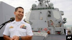In this photo taken Dec. 3, 2010, U.S. navy officer Michael "Vannak Khem" Misiewicz smiles as he delivers his welcome speech on the deck of the U.S. Navy destroyer USS Mustin at Cambodian coastal international see port of Sihanoukville, about 220 kilometers (137 miles) southwest of Phnom Penh, Cambodia. Misiewicz finally returned home Friday as commander of the U.S. Navy destroyer USS Mustin, reuniting with the relatives who wondered whether they would ever see him alive, and the aunt who helped arrange his adoption. His ship departs Monday. (AP Photo/Heng Sinith)