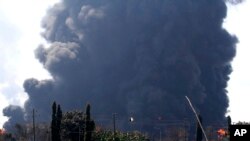 Sebuah mobil melintas sementara asap membubung dari kebakaran yang melanda Kilang Balongan milik Pertamina di Indramayu, Jawa Barat, Indonesia, Senin, 29 Maret 2021. Ratusan orang dievakuasi dari desa terdekat setelah kebakaran besar terjadi di kilang tersebut.