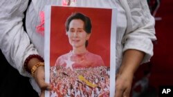 Seorang pengunjuk rasa membawa foto mantan pemimpin Aung San Suu Kyi saat protes peringatan dua tahun pengambilalihan militer di luar Kedutaan Besar Myanmar di Bangkok, Thailand, pada 1 Februari 2023. (Foto: AP)