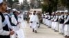Sejumlah siswa memegang bendera Taliban ketika menyambut otoritas yang datang berkunjung Sekolah Menengah Amani di Kabul pada 20 Maret 2024 dalam upacara peringatan tahun ajaran baru. (Foto: AFP/Wakil Kohsar)