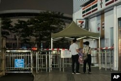 Warga mengamati pembatas di pintu masuk tempat seorang pria dengan sengaja menabrakkan mobilnya ke orang-orang yang tengah berolahraga, menewaskan beberapa orang di Zhuhai, Guangdong, China selatan, 12 November 2024. (Ng Han Guan/AP)