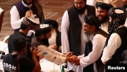 Delegasi Taliban berjabat tangan selama pembicaraan antara pemerintah Afghanistan dan gerilyawan Taliban di Doha, Qatar 12 September 2020. (Foto: REUTERS/Ibraheem al Omar)