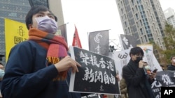 FILE - A supporter holds a sign reading "Support press freedom in Hong Kong" in a protest outside the Bank of China in Taipei, Dec. 30, 2021.