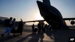 Pripadnik vazduhoplovnih snaga SAD usmerava ljude koji se evakuišu i ukrcavaj u američki vojni transportni avion C-17 Glubmaster III, na aerodromu Hamid Karzai, u Kabulu, Avganistan, 24. avgusta 2021, na fotografiji koju su objavile Vazduhoplovne snage SAD.