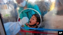 印度一位医护人员在对一名儿童进行新冠病毒感染检测。（美联社图片）