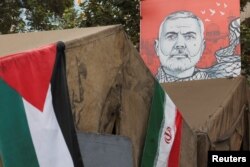 Spanduk bergambar mendiang pemimpin Hamas Ismail Haniyeh berada di samping bendera Iran dan Palestina di Teheran, Iran, 12 Agustus 2024. (Foto: Majid Asgaripour/WANA via REUTERS)