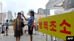 지난해 8월 북한 평양역에서 역무원이 승객의 체온을 재고 있다.