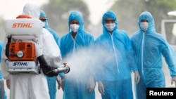 រូបឯកសារ៖ ក្រុម​គ្រូពេទ្យ​ក្នុង​ឯកសណ្ឋាន​ការពារ​ពណ៌ស បាញ់​ថ្នាំ​សម្លាប់​មេរោគ​ដល់​កម្មករ​សំណង់​វៀតណាម ដើម្បី​បង្ការ​ជំងឺ​កូវីដ១៩ ទីក្រុង​ហាណូយ ប្រទេស​វៀតណាម ថ្ងៃទី២៩ ខែកក្កដា ឆ្នាំ២០២០។ 