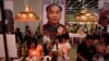 FILE - Book lovers read beneath poster promoting "Stange Leung Chun-ying," which depicts the new Hong Kong Chief Executive as the late Chinese leader Mao Zedong, Hong Kong Book Fair, July 18, 2012.