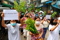 Anti-coup protesters hold leaf branches and signs to welcome the NUG, or National Unity Government, as they march April 17, 2021, in Yangon, Myanmar.