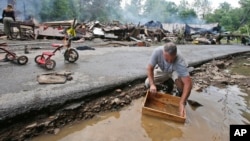 马克·莱斯特6月24日在所居住的西弗吉尼亚州白硫磺泉镇遭遇严重洪水之后，正在进行清理，用溪水清洗一个盒子。