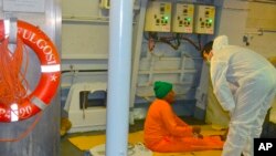 Seorang anggota Angkatan Laut Italia membantu seorang migran yang baru saja diselamatkan dekat pulau Lampedusa (25/10). 