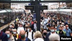 Orang-orang mengenakan masker berjalan di peron di Stasiun King's Cross di tengah pandemi COVID-19, di London, Inggris, 12 Juli 2021. 