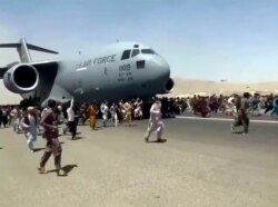 Hundreds of people run alongside a U.S. Air Force C-17 transport plane as it moves down a runway of the international airport, in Kabul, Afghanistan, Aug.16. 2021. (Verified UGC via AP)