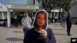 香港电台的员工头戴新闻主播利君雅的面罩在广播大楼外进行静默抗议。（2021年1月28日）