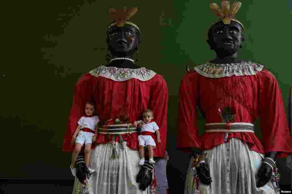 Children pose with two giants during San Fermin festival's "Comparsa de gigantes y cabezudos" (Parade of the Giants and Big Heads) in Pamplona, Spain.