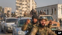 叙利亚反政府武装占领中部城市哈马，战士们在街上巡逻。(美联社：2024年12月6日)