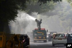Kendaraan pemerintah Delhi menyemprotkan air untuk mengendalikan polusi udara saat lapisan kabut asap tebal menyelimuti kota tersebut, New Delhi, India, Kamis, 14 November 2024. (Foto: Manish Swarup/AP)