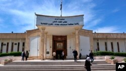 FILE - People walk outside Iraqi Criminal Court in Baghdad's Karkh district, Iraq, May 5, 2019. On Wednesday, a wife of deceased Islamic State leader Abu Bakr al-Baghdadi was sentenced to death for allegedly helping detain Yazidi women.  