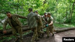 Українські військовослужбовці тягнуть колоду для "посилення своєї позиції на передовій" біля міста Кремінна, Донецька область, 25 квітня 2024 року, - Радіо Вільна Європа/Радіо Свобода/Сергій Нужненко через REUTERS