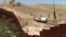 The view from the Mexican side as a U.S. Border Patrol car passes a fence. (G. Flakus/VOA)