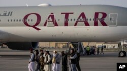 Pejuang Taliban tampak berjalan melewati pesawat Qatar Airways di Bandara di Kabul, Afghanistan, pada Kamis September 2021. Sekitar 200 warga asing, termasuk warga Amerika di dalamnya, diangkut oleh pesawat tersebut keluar dari Afghanistan. (Foto:AP Photo/Bernat Armangue)