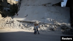 宰牲节庆祝的第一天，两个男孩在大马士革郊区一栋废弃的建筑物边散步(2016年9月12日)