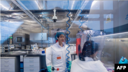 资料照：武汉病毒研究所的病毒学家石正丽（左）在该所的P4实验室内。