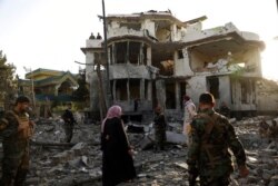FILE - Afghan security personnel inspect a damaged building in the aftermath of an attack in Kabul, Afghanistan, Aug. 4, 2021.