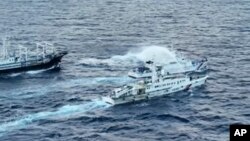 Kapal penjaga pantai China, bawah, menggunakan meriam air sementara di dekatnya, kapal patroli penjaga pantai Filipina, BRP Cabra, saat kedua kapal mendekati Second Thomas Shoal di Laut Cina Selatan yang disengketakan pada 10 Desember 2023 lalu (foto: ilustrasi).