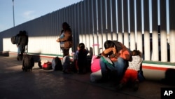 Arhiva - Migrant sedi sa svijom decom dok čekaju da čuju da li je njihov broj prozvan za apliciranje za azilu u SAD, na granici SAD i Meksika, u Tihuani, Meksiko, 25. januara 2019.