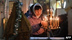 一名女子在乌克兰哈尔科夫的一座教堂里参加东正教圣诞节弥撒时点亮蜡烛。（2023年12月24日）