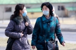 People wear masks to protect from a new coronavirus as they walk through the Kwangbok Street in Pyongyang, North Korea, Feb. 26, 2020.