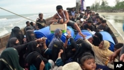 Seorang pria Aceh membagikan makanan kepada pengungsi Rohingya di atas perahu yang terdampar di pantai di Peureulak, Aceh, 29 Januari 2025. (Foto: AP)