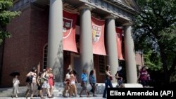 FILE - People are led on a tour on the campus of Harvard University in Cambridge, Massachusetts. Refugees worldwide will be able to take more than 1,000 online university courses for free.