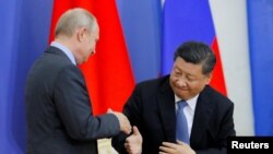 Presiden China Xi Jinping dan Presiden Rusia Vladimir Putin berjabat tangan di St. Petersburg, Rusia, 6 Juni 2019. (Foto: Dmitri Lovetsky via REUTERS)
