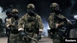 Petugas penegak hukum federal terlihat siaga penuh selama berlangsungnya aksi demo menentang kehadiran petugas penegak hukum federal dan ketidaksetaraan ras di Portland, Oregon, AS, 21 Juli 2020. (REUTERS / Caitlin Ochs)