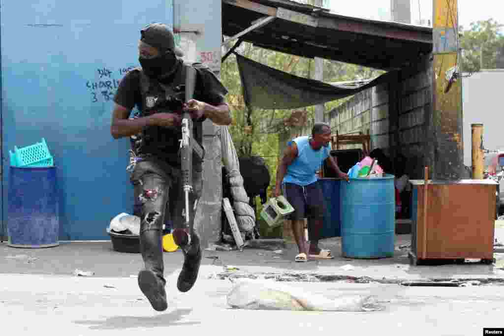 A police officer runs during a clash with gangs as a resident of the Delmas 30 neighborhood flees his home due to gang violence, in Port-au-Prince, Haiti, Feb. 26, 2025.