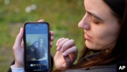 Julija Fedosjuk pokazuje svoju i suprugovu fotografiju tokom intervjua za Asošijeted pres u aprilu 2022. godine.