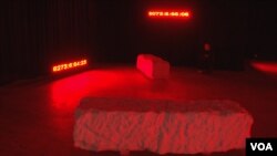 Prostorija sa teškim kamenovima koji izgledaju kao grobnice i digitalnim satovima koji mere vreme od kada su pojedine osobe nestale na izložbi "Bolje grob nego da se ne zna" u Prištini (Foto: VOA)