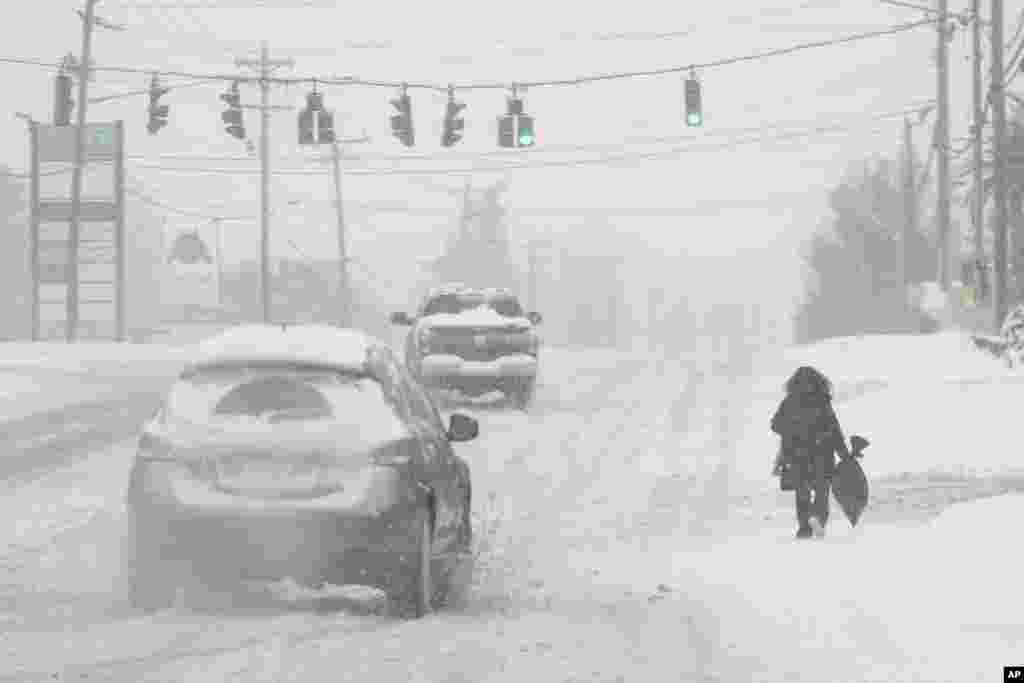 Heavy snow falls as a person walks along U.S. Route 42 in Florence, Kentucky, Jan. 6, 2025. 