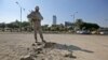 A member of the Iraqi security forces inspects the damage outside the Zawraa park in the capital Baghdad, Nov. 18, 2020, after volley of rockets slammed into the Iraqi capital breaking a month-long truce on attacks against the U.S. embassy.