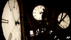 FILE - Custodian Ray Keen inspects a clock face before changing the time on the 100-year-old clock atop the Clay County Courthouse, March 8, 2014, in Clay Center, Kansas. (AP Photo/Charlie Riedel, File)