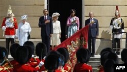 Tổng thống Obama và Ðệ nhất phu nhân Michelle đứng trên bực thềm của Ðiện Buckingham cùng với Nữ hoàng Elizabeth, Hoàng thân Philip và Thái tử Charles cùng phu nhân Camilla trong khi các binh sĩ Anh trong đội 'Ngự lâm quân Scotland' trình tấu quốc ca của 