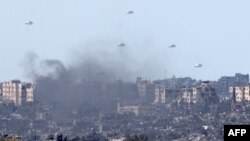 Humanitarian aid falls over northern Gaza as seen from Israel's southern border with the Gaza Strip on March 7, 2024, amid the ongoing conflict between Israel and the Palestinian group Hamas.
