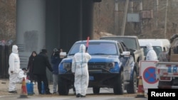 北京房山地区发现非洲猪瘟后，身穿防护服的防疫人员在通往出现疫情的村庄道路上设卡。（2018年11月23日）