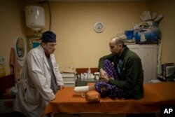 FILE - Ukrainian doctor Yurii Kuznetsov speaks to land mine victim Oleksandr Kolisnyk at the hospital in Izium, Ukraine, on Feb. 19, 2023.