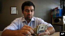 FILE-- An Iranian currency exchange bureau worker counts U.S. dollars in Tehran, April 5, 2015. In January 2016, Iran transferred some frozen overseas assets following the implementation of the nuclear deal with world powers.
